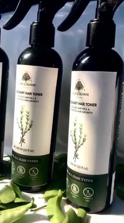 Two Rosemary Hair Toner bottles standing together with fresh leaves